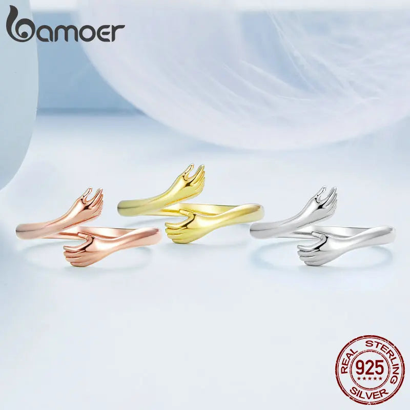 Sterling Silver Warmth Adjustable Ring in various finishes showcasing hand-hug design symbolizing care and connection.